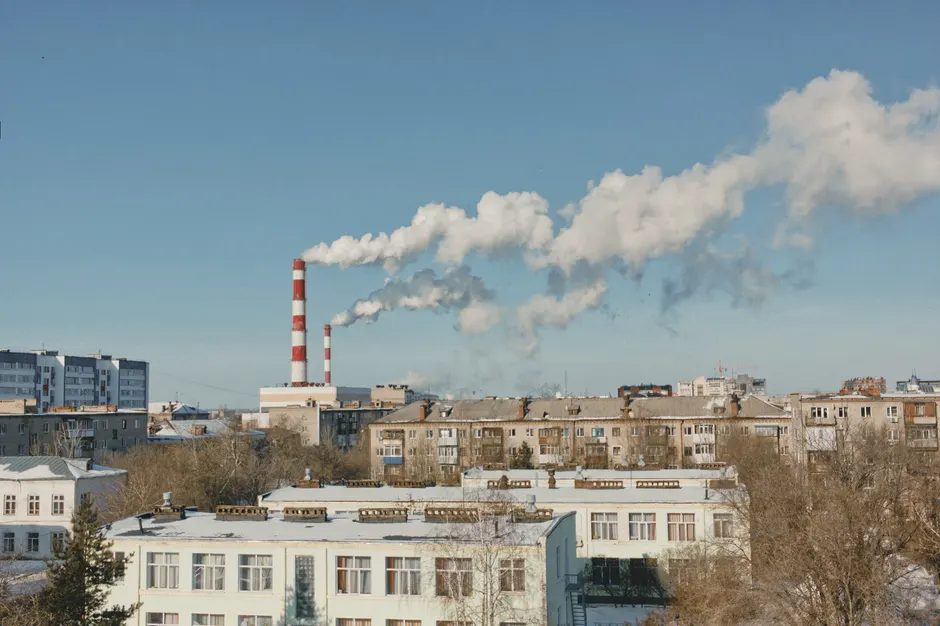 Cityscape with smoking chimneys and clear sky, depicting industry.